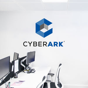 Modern office space with multiple computer desks and "CYBERARK" logo on the wall.