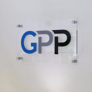 Clear acrylic sign with 'GPP' logo in blue, grey, and black mounted on a wall.